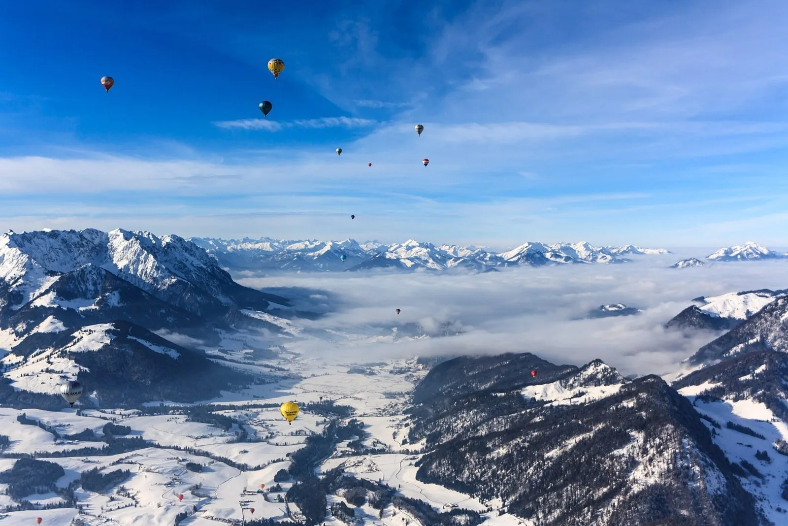 Mongolfiere colorate in volo su vallate alpine innevate in una giornata limpida d'inverno